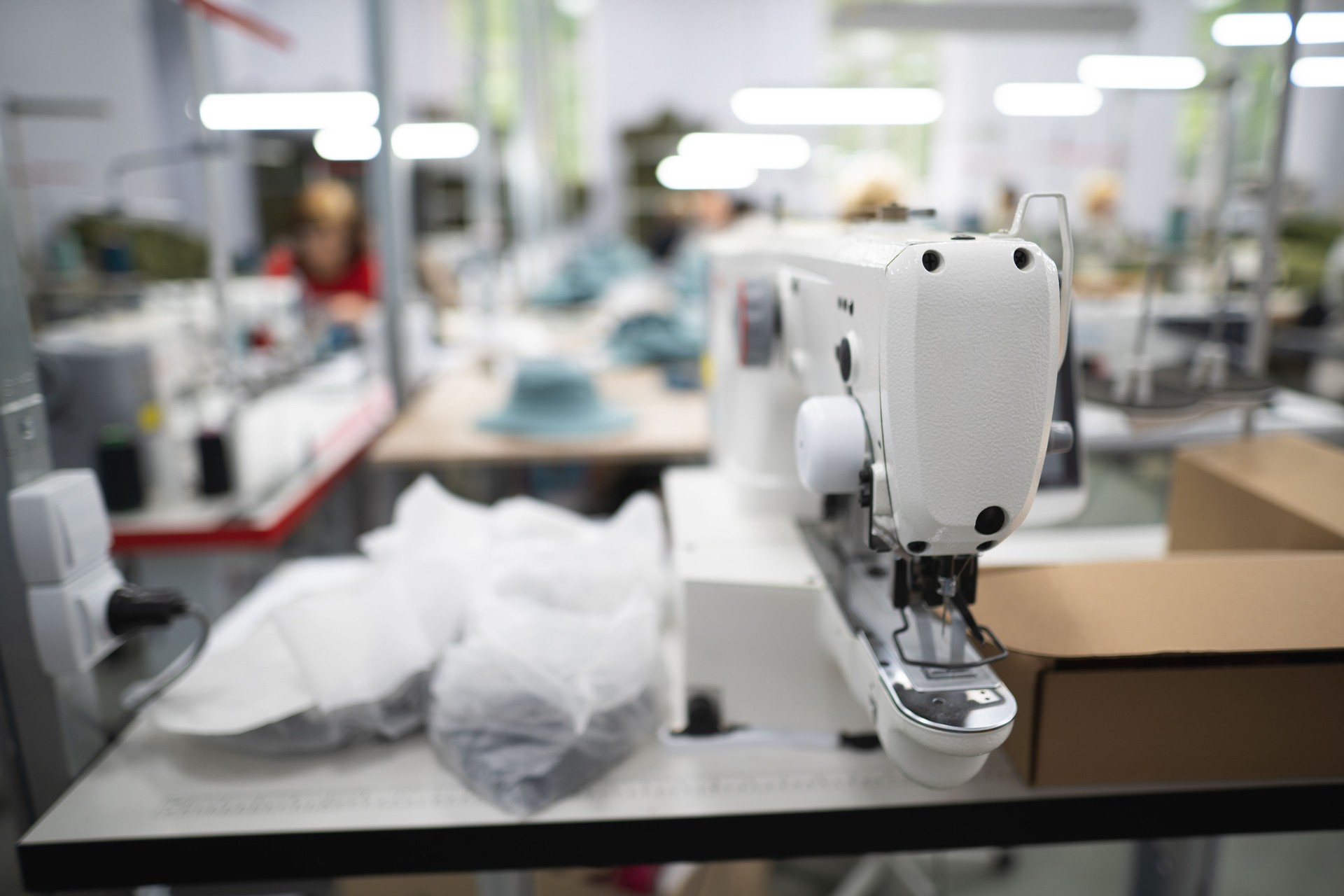 Los trabajadores de una fábrica industrial de prendas de vestir cosen ropa en una máquina de coser